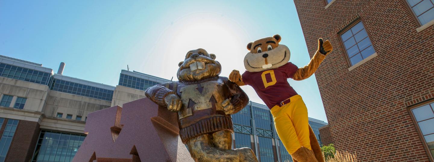 Goldy mascot posing next to Goldy statue