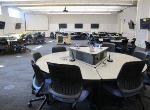 Classroom interior featuring round tables and remote learning technology