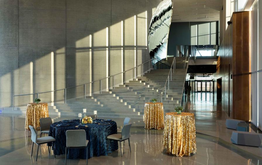 Reception space inside the Bell Museum featuring decorated tables, curving concrete wall, and high ceilings